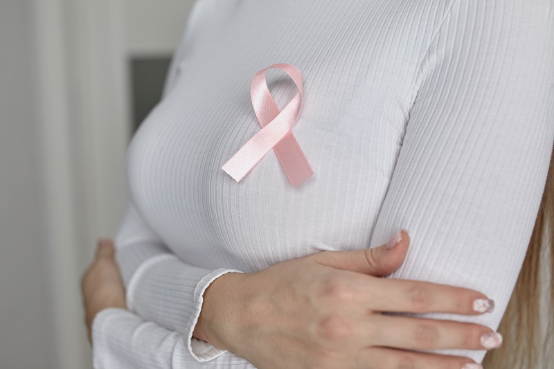 A woman in a white sweater with a pink fly in support of breast cancer patients. Ювенільний рак молочної залози